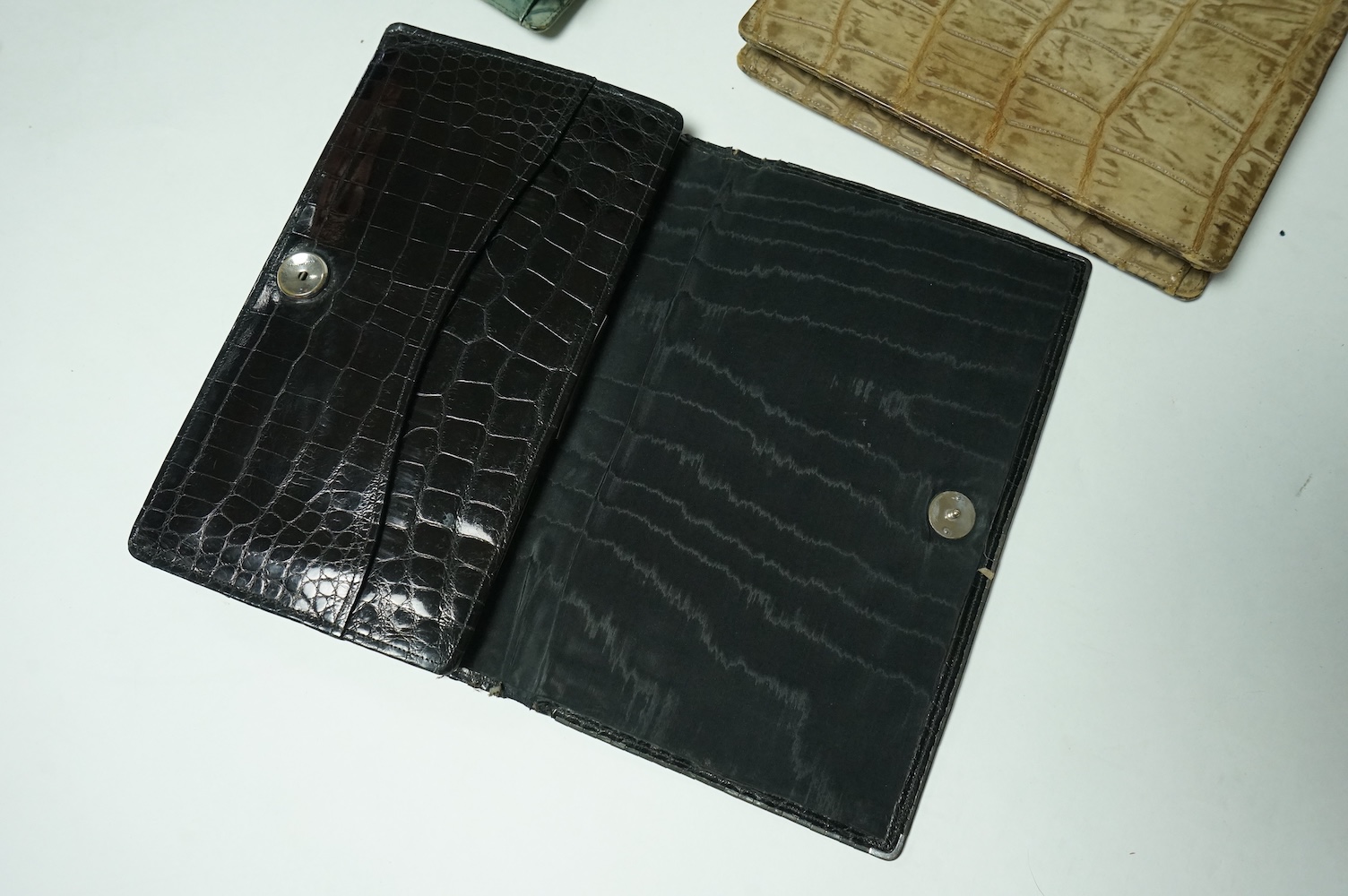 Three stylish Art Deco ladies handbags. A black crocodile clutch bag with an MMW monogram and silver mounted edge and two smaller handbags, one green the other brown, both faux crocodile with stylish bakelite clasps. Clu